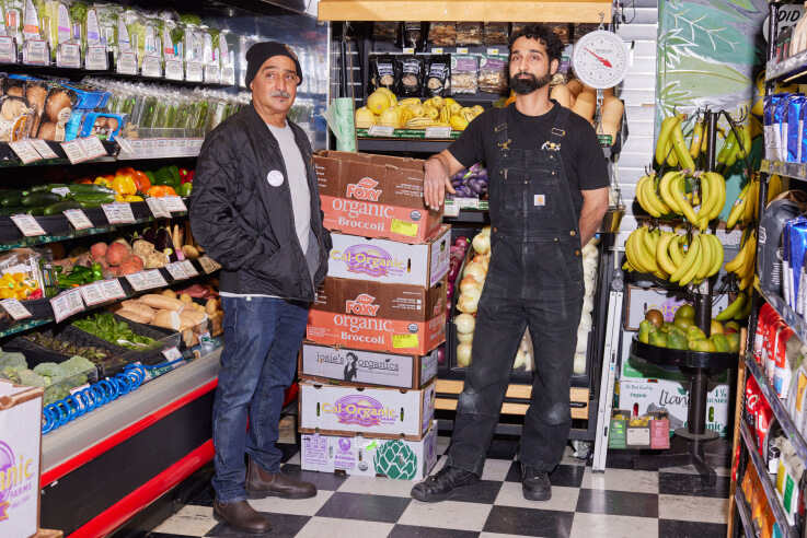 Le Beau Market business owners are standing in their grocery store.