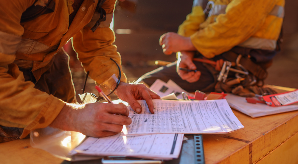 Construction workers completing business license paperwork at a job site.