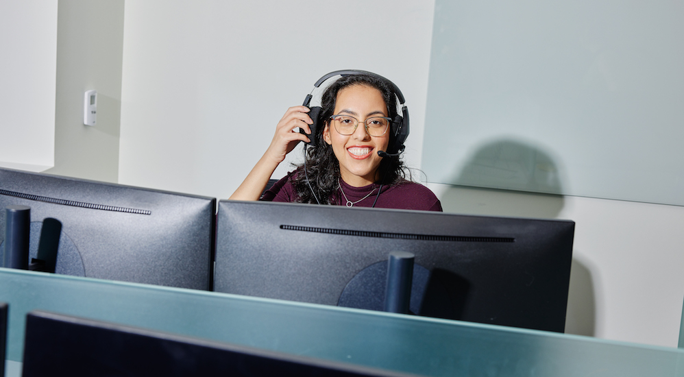 A NEXT claims advocate with a headset on at a desk with a computer.