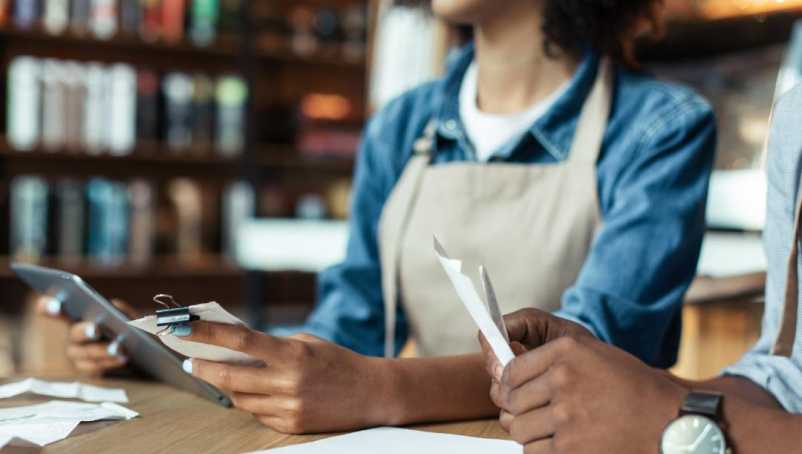 Two business owners sit at a table reviewing paperwork.