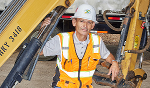 construction worker in front of equipment wearing vest