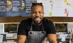 restaurant owner receiving orders at the counter in front of a menu