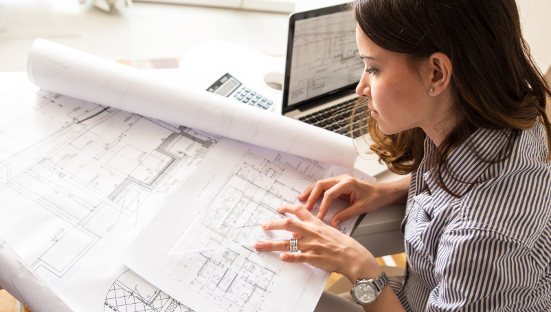 An architect reviews blueprints at a desk.