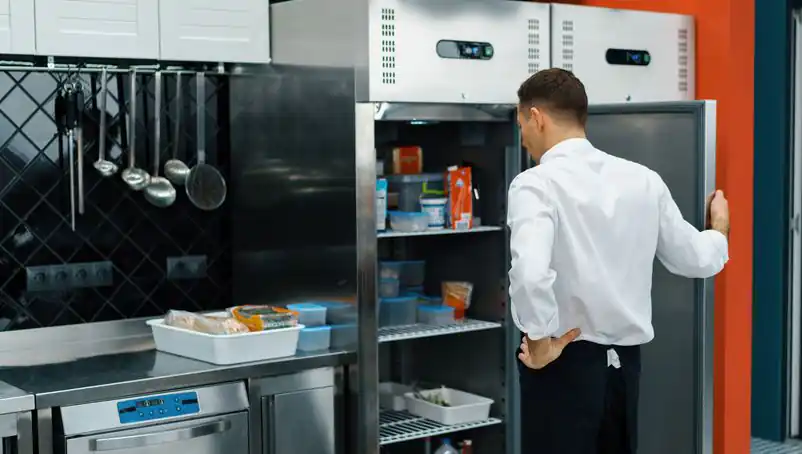 restaurant worker looking inside a commercial refrigerator