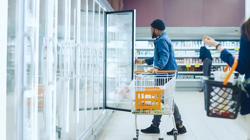 person stands in front of a grocery store refrigerator