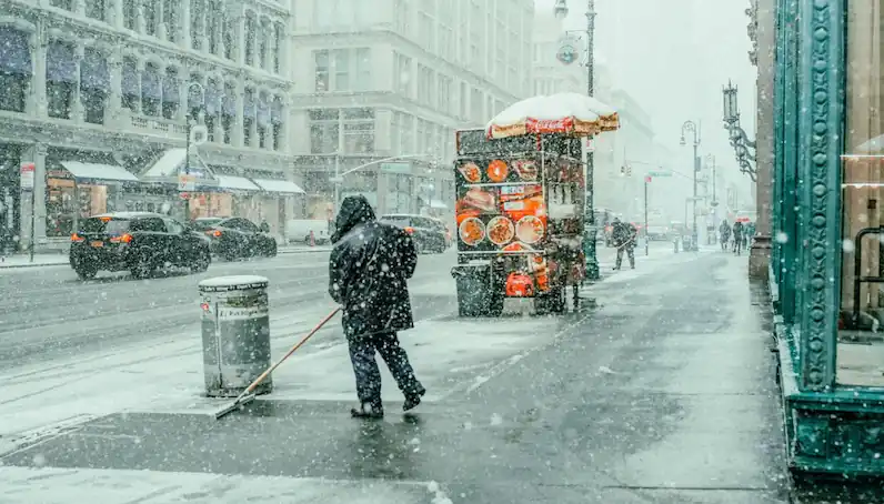 person shovels snow in front of a business