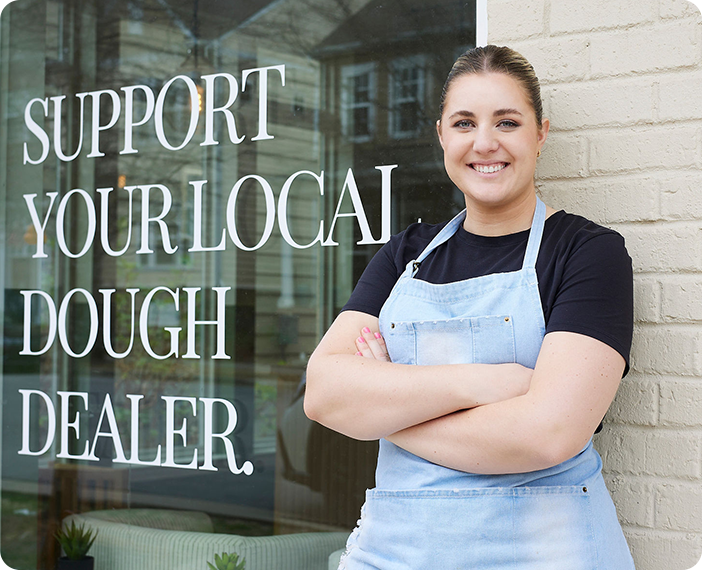 baker standing in front of her shop